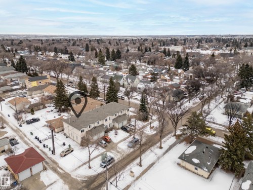 An aerial view showcasing the property with a light-colored exterior and a dark roof, surrounded by paved areas and mature trees - 8109 85 Street, Edmonton, AB - Outdoor With View