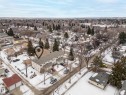 An aerial view showcasing the property with a light-colored exterior and a dark roof, surrounded by paved areas and mature trees - 8109 85 Street, Edmonton, AB  - Outdoor With View 