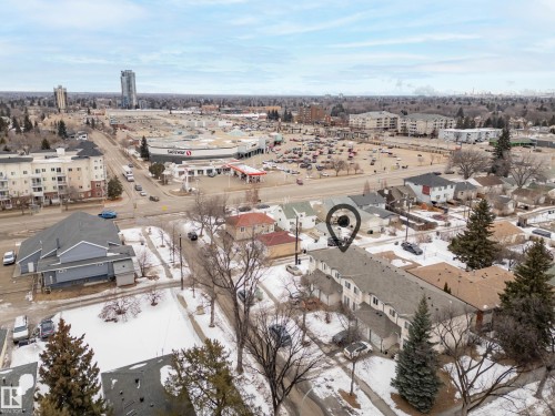 Aerial view showcasing the property's proximity to a commercial center with a large grocery store and retail spaces, along with other residential buildings and tree-lined streets - 8109 85 Street, Edmonton, AB - Outdoor With View