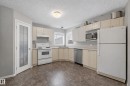 The kitchen features light-toned cabinetry, a white refrigerator, a white range, a stainless steel dishwasher, and a window with a view - 8109 85 Street, Edmonton, AB  - Indoor Photo Showing Kitchen 