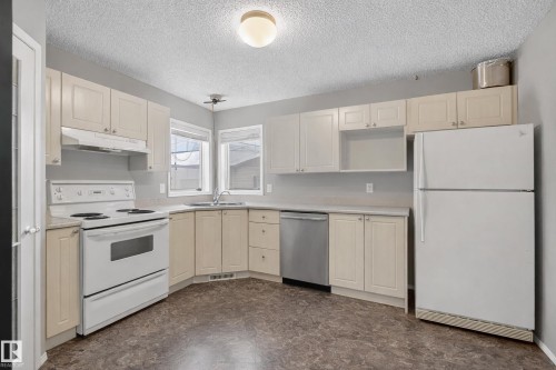 The kitchen features ample cabinetry, a white refrigerator, and a white electric range - 8109 85 Street, Edmonton, AB - Indoor Photo Showing Kitchen