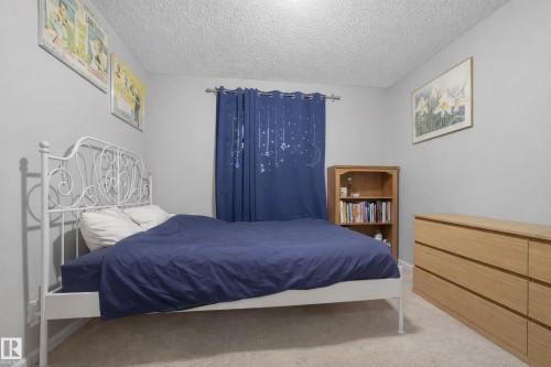 This room features carpeted flooring, light grey walls, and a window with dark blue curtains - 8109 85 Street, Edmonton, AB - Indoor Photo Showing Bedroom