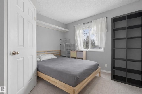 The room features light gray walls, a window with white curtains, and light-colored carpeting - 8109 85 Street, Edmonton, AB - Indoor Photo Showing Bedroom