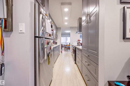 The kitchen features light-colored flooring, stainless steel appliances, and grey cabinetry with silver handles - 803 12303 Jasper Avenue, Edmonton, AB - Indoor