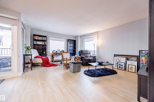 This spacious living area features light-colored flooring, windows providing natural light, and a patio door leading to an outdoor space - 803 12303 Jasper Avenue, Edmonton, AB - Indoor Photo Showing Living Room