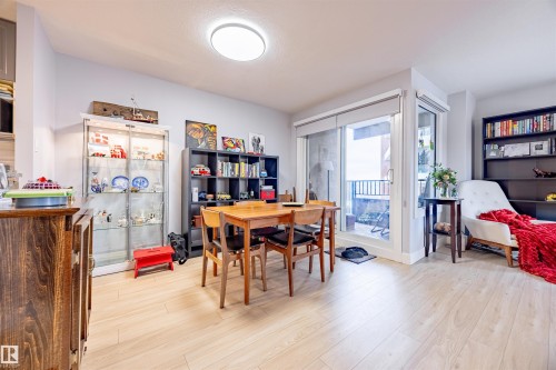 The property features light-toned flooring throughout, a dining area with a wooden table and chairs, and sliding glass doors leading to an outdoor space - 803 12303 Jasper Avenue, Edmonton, AB - Indoor