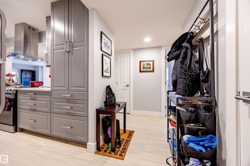 The kitchen features gray cabinetry with brushed nickel hardware, a stainless steel range hood, and a light-colored countertop - 803 12303 Jasper Avenue, Edmonton, AB - Indoor Photo Showing Other Room