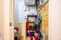 Utility room with white walls, a chest freezer, and a wooden accent wall with hooks - 