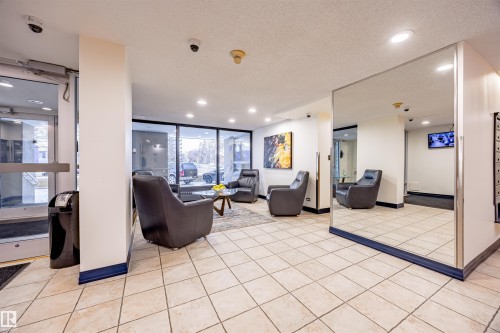 The property features an inviting common area with large windows, tiled flooring, and recessed lighting - 803 12303 Jasper Avenue, Edmonton, AB - Indoor Photo Showing Other Room