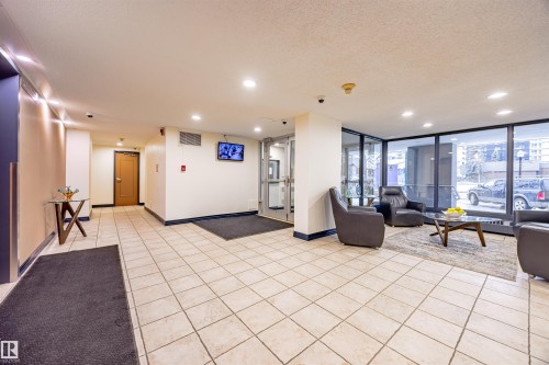 The property features a common area with large windows, light-colored tiled flooring, and recessed lighting - 803 12303 Jasper Avenue, Edmonton, AB - Indoor
