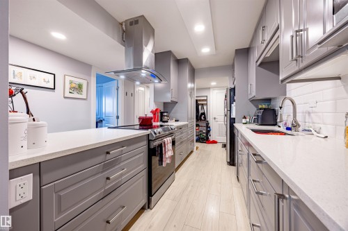 The kitchen features gray cabinetry, white countertops, a stainless steel range hood, and a white subway tile backsplash - 803 12303 Jasper Avenue, Edmonton, AB - Indoor Photo Showing Kitchen