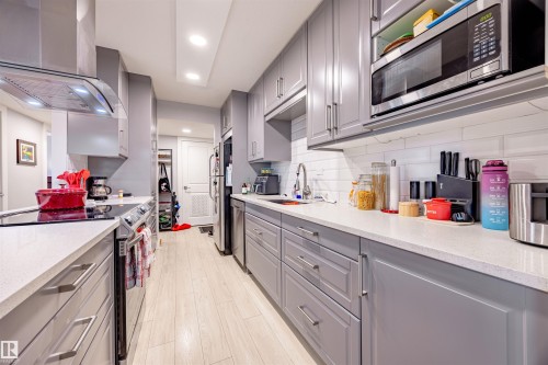 The kitchen features light grey cabinetry, stainless steel appliances, white subway tile backsplash, and light-colored countertops - 803 12303 Jasper Avenue, Edmonton, AB - Indoor Photo Showing Kitchen