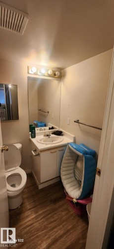 The bathroom features wood-look flooring, a white vanity with an integrated sink, a mirror, and overhead lighting - 204 11218 80 Street, Edmonton, AB - Indoor Photo Showing Bathroom