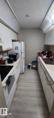 Kitchen featuring white cabinetry, a refrigerator, an electric stove, and a sink - 204 11218 80 Street, Edmonton, AB - Indoor Photo Showing Kitchen