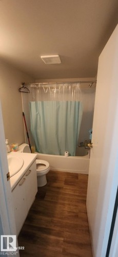 The bathroom features wood-look flooring, a white vanity with a rectangular sink, a toilet, and a shower-over-bath combination - 204 11218 80 Street, Edmonton, AB - Indoor Photo Showing Bathroom