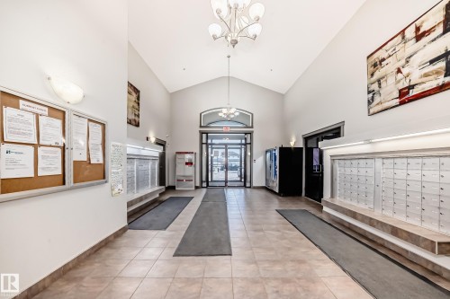 The property features a spacious lobby with vaulted ceilings, tiled flooring, and a chandelier - 102 111 Edwards Drive, Edmonton, AB - Indoor Photo Showing Other Room