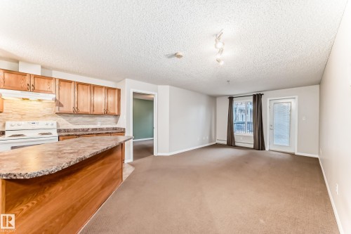 Open concept living area with brown carpeting and light gray walls - 102 111 Edwards Drive, Edmonton, AB - Indoor Photo Showing Kitchen