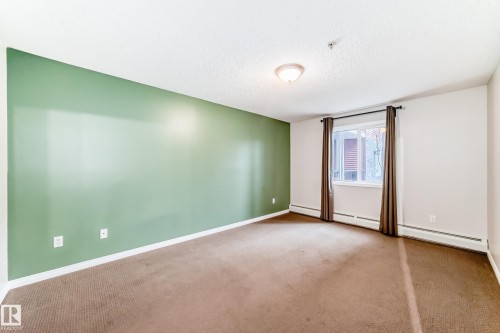 This room features a window with curtains, carpeted flooring, and a ceiling light fixture - 102 111 Edwards Drive, Edmonton, AB - Indoor Photo Showing Other Room