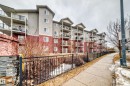 The property features a multi-story building with light-colored siding and a red brick base, each level including balconies with dark railings - 102 111 Edwards Drive, Edmonton, AB  - Outdoor 