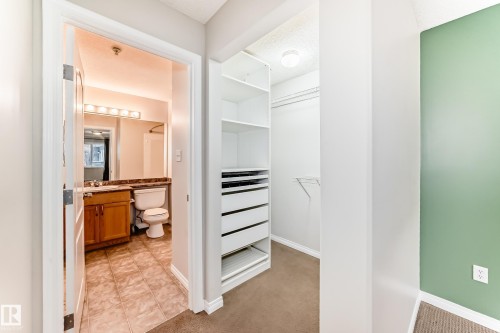 Bathroom featuring a vanity with a wood cabinet, a mirror with strip lighting, and a toilet - 102 111 Edwards Drive, Edmonton, AB - Indoor Photo Showing Other Room