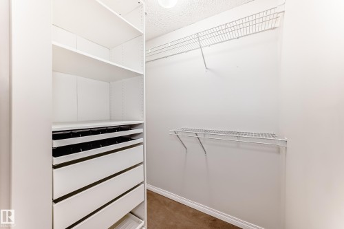 Walk-in closet featuring white built-in shelving, white drawers, and wire shelving - 102 111 Edwards Drive, Edmonton, AB - Indoor With Storage