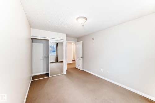 This room features light-colored walls and brown carpeting - 102 111 Edwards Drive, Edmonton, AB - Indoor Photo Showing Other Room
