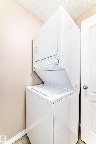 The property includes a white stacked washer and dryer unit - 102 111 Edwards Drive, Edmonton, AB - Indoor Photo Showing Laundry Room