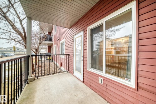 This property features a concrete patio with a black metal railing - 102 111 Edwards Drive, Edmonton, AB - Outdoor With Deck Patio Veranda With Exterior