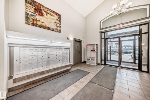 Well-maintained entrance area featuring tile flooring, a mailroom wall, and double glass doors - 102 111 Edwards Drive, Edmonton, AB - Indoor Photo Showing Other Room