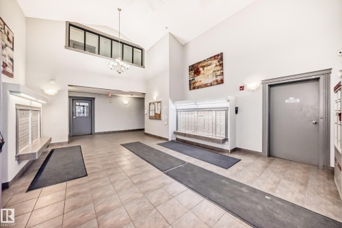 The property features a spacious entrance hall with high vaulted ceilings and tiled flooring - 102 111 Edwards Drive, Edmonton, AB - Indoor Photo Showing Other Room