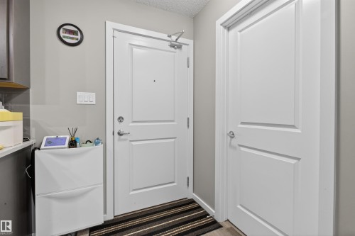 Entryway with two paneled doors, light grey walls, and a striped floor mat - 134 148 Ebbers Boulevard, Edmonton, AB - Indoor Photo Showing Other Room