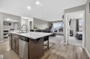 The property features an open-concept living area with a kitchen island, stainless steel dishwasher, and sliding glass doors - 134 148 Ebbers Boulevard, Edmonton, AB  - Indoor Photo Showing Kitchen 