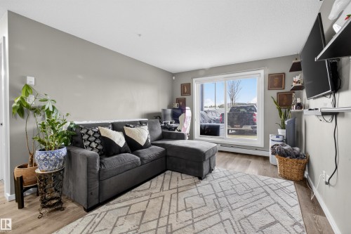Living area featuring light gray walls, a sliding glass door, and wood-style flooring - 134 148 Ebbers Boulevard, Edmonton, AB - Indoor Photo Showing Living Room