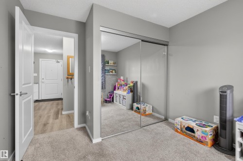 This room features a mirrored closet with sliding doors, neutral grey walls, and light-colored carpeting - 134 148 Ebbers Boulevard, Edmonton, AB - Indoor