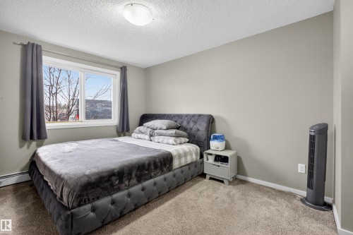 This room features a window with grey curtains, light neutral colored walls, and carpeted flooring - 134 148 Ebbers Boulevard, Edmonton, AB - Indoor Photo Showing Bedroom