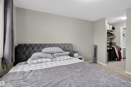 This room features light gray walls, a textured ceiling, and carpeted flooring - 134 148 Ebbers Boulevard, Edmonton, AB - Indoor Photo Showing Bedroom