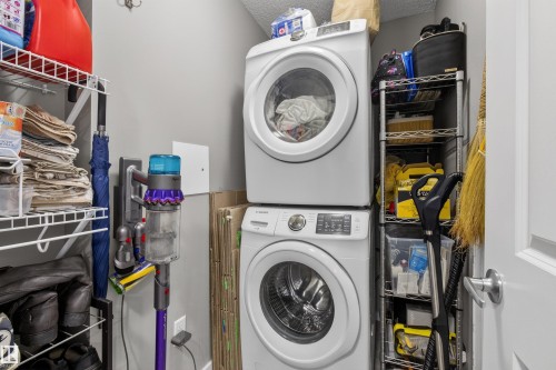 Dedicated laundry area featuring a stacked washer and dryer, along with built-in wire shelving for organized storage - 134 148 Ebbers Boulevard, Edmonton, AB - Indoor Photo Showing Laundry Room