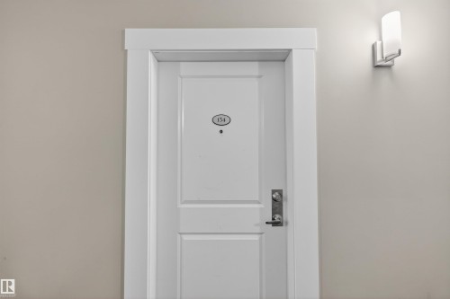 The property entrance features a white paneled door with a modern door handle and a contemporary wall sconce providing illumination - 134 148 Ebbers Boulevard, Edmonton, AB -  Photo Showing Other Room