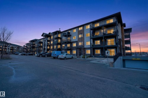 The building features an exterior with balconies and a visible underground parking entrance - 134 148 Ebbers Boulevard, Edmonton, AB - Outdoor With Facade