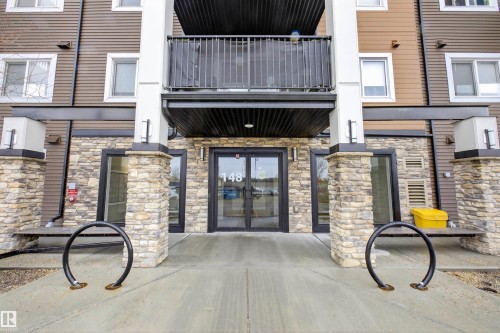 The property features a stone facade on the ground level, contrasting with the brown siding and white trim of the upper floors - 134 148 Ebbers Boulevard, Edmonton, AB - Outdoor