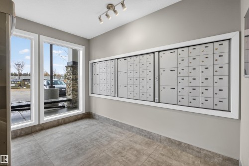 The property features large windows, modern track lighting, and a wall of mailboxes - 134 148 Ebbers Boulevard, Edmonton, AB - Indoor Photo Showing Other Room