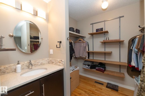 The vanity features a light-colored countertop with an oval sink and a modern faucet, complemented by an oval mirror and a light fixture with three rectangular lights - 54 Beaverbrook Crescent, St. Albert, AB - Indoor Photo Showing Bathroom