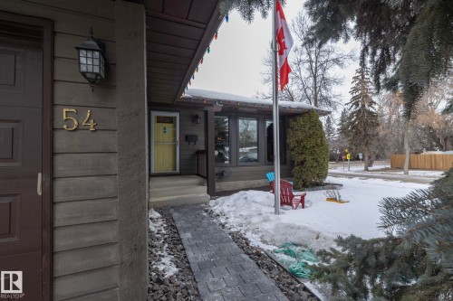 The property features horizontal siding, a paved walkway, and an inviting entryway with a yellow door - 54 Beaverbrook Crescent, St. Albert, AB - Outdoor