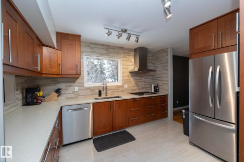 The kitchen features wood cabinetry, light countertops, a stainless steel refrigerator, and a window above the sink - 54 Beaverbrook Crescent, St. Albert, AB - Indoor Photo Showing Kitchen With Stainless Steel Kitchen With Double Sink