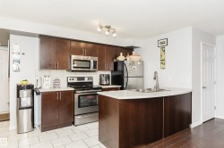 The kitchen features dark wood cabinetry, stainless steel appliances, and a kitchen island with a double sink - 