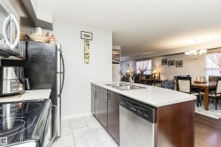 The kitchen features a stainless steel refrigerator, microwave, and dishwasher, with a double basin sink and dark wood cabinetry - 