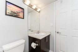 A well-appointed bathroom featuring a white toilet, a vanity with an integrated sink, and a mirror with overhead lighting - 