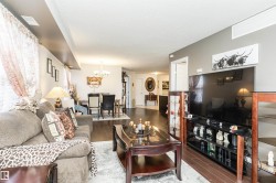 Living area featuring dark wood flooring, light grey walls, and ample natural light from the window - 