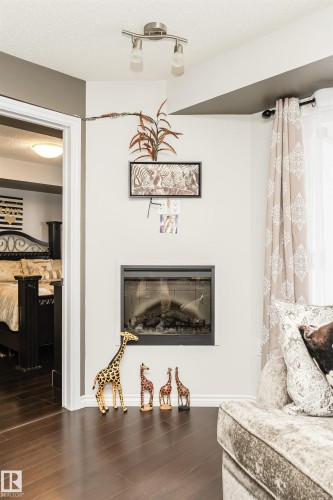 This inviting space features dark hardwood flooring, a built-in fireplace, and track lighting on the ceiling - 107 10118 106 Avenue, Edmonton, AB - Indoor Photo Showing Living Room
