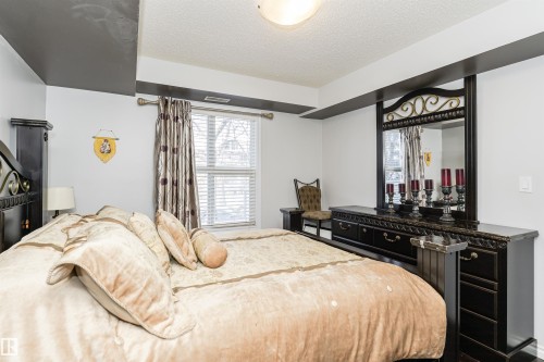 The property features a bedroom with a large window, providing natural light, and a decorative headboard - 107 10118 106 Avenue, Edmonton, AB - Indoor Photo Showing Bedroom